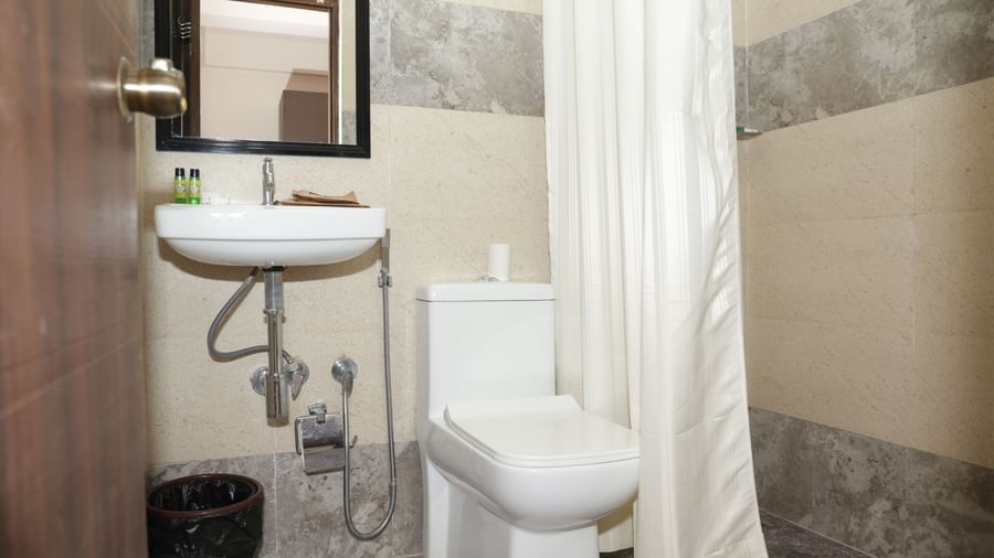 A bathroom at Nazri The Verda Hotel, Arambol, equipped with a sink, mirror, toilet, and shower with curtain.