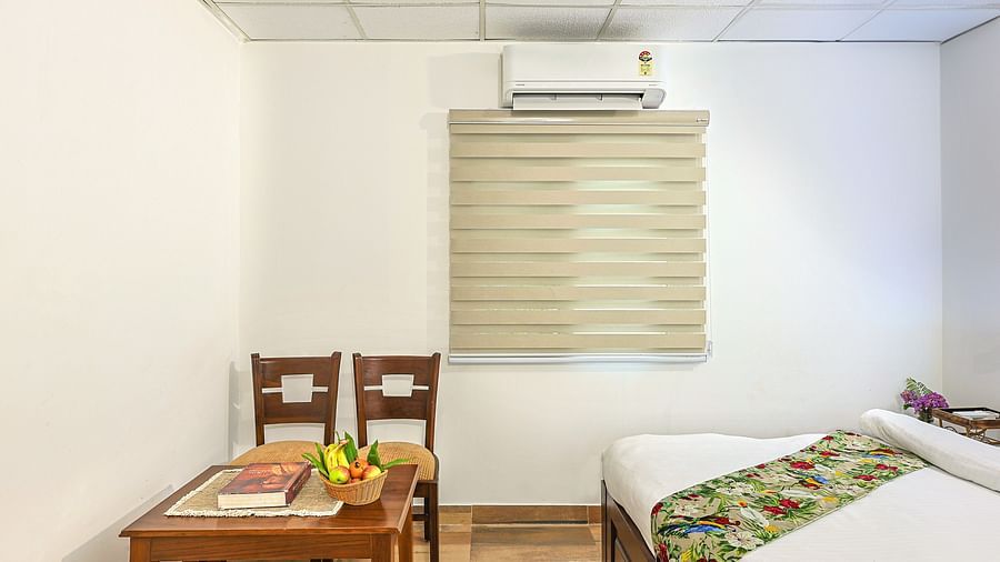 a double bed with a bed runner on it and chairs and a small table opposite it inside one of the rooms - neer ganga resorts