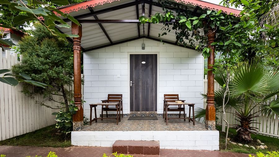 the back view of the room with a balcony having chairs and tables under a canopy inside one of the rooms - Neer ganga Resorts