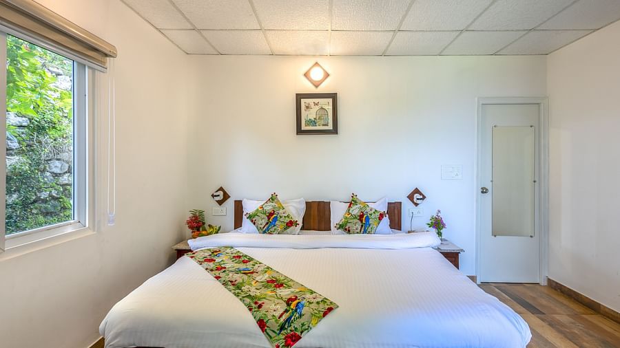 a double bed with a bed runner and many pillows on it inside one of the rooms - Neer ganga Resorts