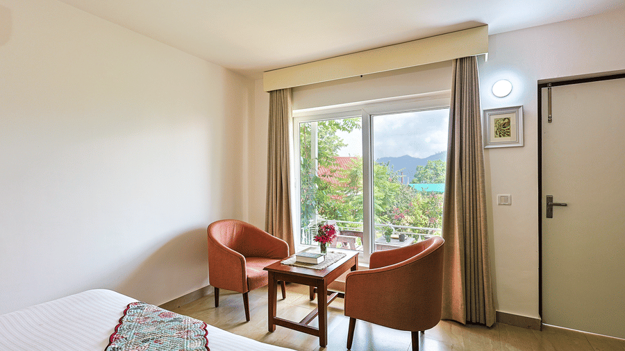 chairs and a small table in between next to the window inside one of the rooms - Neer Ganga Resorts