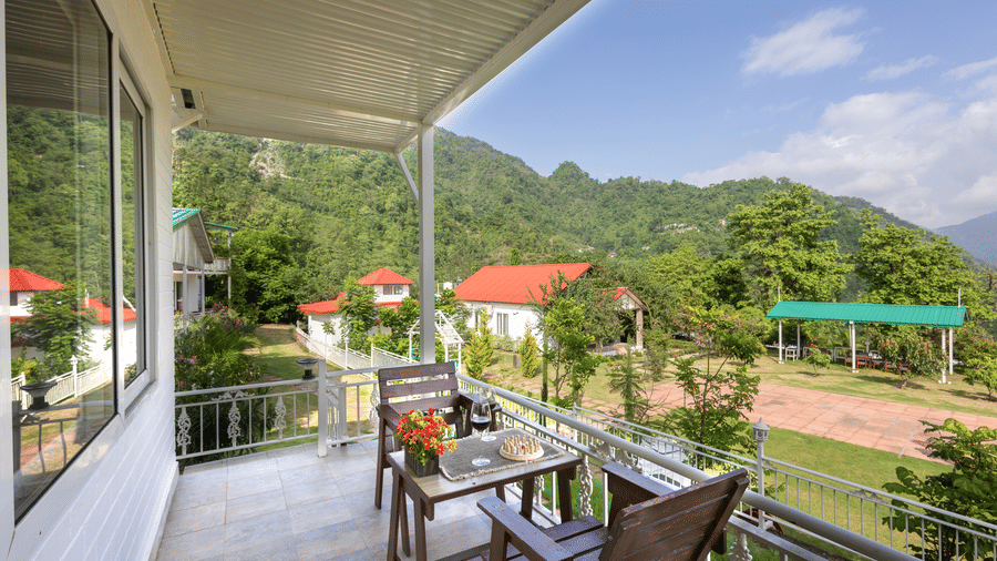 chairs outside the room on the balcony with trees in the background - Neer Ganga Resorts