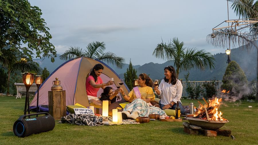a group of women tenting on a garden area with a bonfire next to them - neer ganga resorts