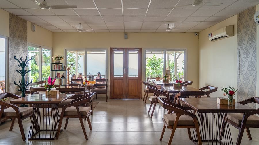 Indoor sitting area with tables and chairs in the restaurant at Neer Ganga Resorts