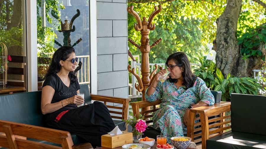 Two women sitting in the open area and enjoying a meal at Neer Ganga Resorts