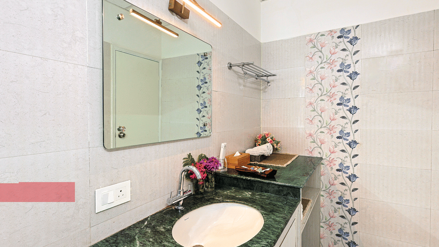 A bathroom at Neer Ganga with a sink, a mirror, and toileteries.