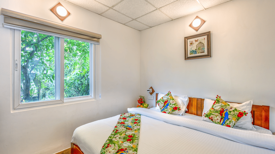 A room at Neer Ganga with a large bed, spreads, pillows, a window, and a wall art.