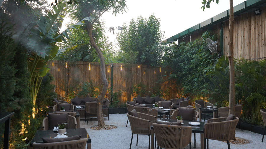 Nemesia features an outdoor space with seating arrangements and subtle lighting amidst foliage.