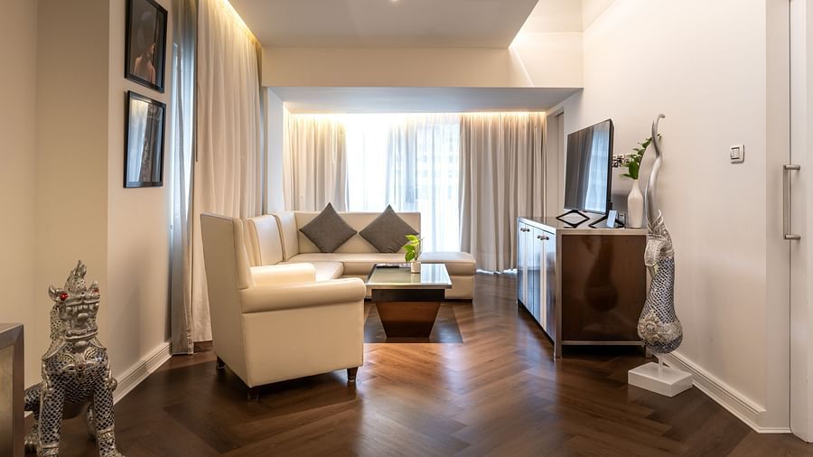 A modern living room featuring designer sofas and a TV atop a wooden table - Night Hotel Bangkok