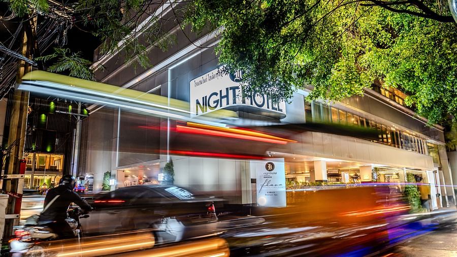 A picture showing Night Hotel Bangkok's Facade with vehicles travelling on the road.