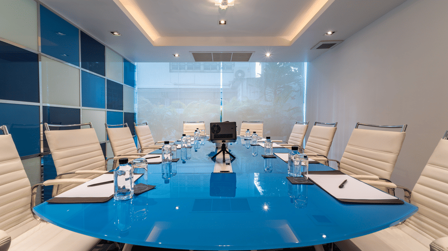 Seating arrangement inside the Boardroom with white chairs and blue table - Night Hotel Bangkok