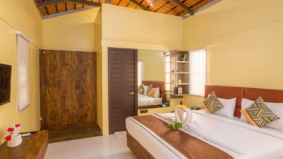 Well-lit bedroom with twin beds and rustic ceiling – Nirantara Resort & Spa