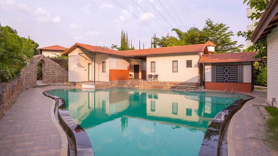 Outdoor swimming pool with cottages in the background – Nirantara Resort & Spa
