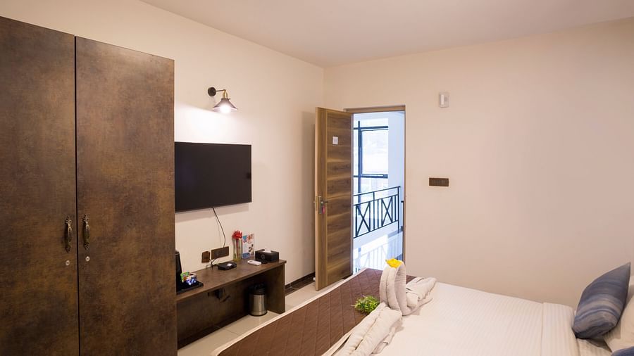 Room with double bed, wardrobe, and work desk – Nirantara Resort & Spa