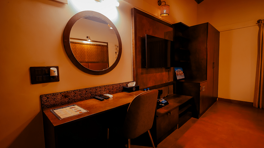 A room with a desk, mirror, and a partially visible bed at Nirantara Resort & Spa.