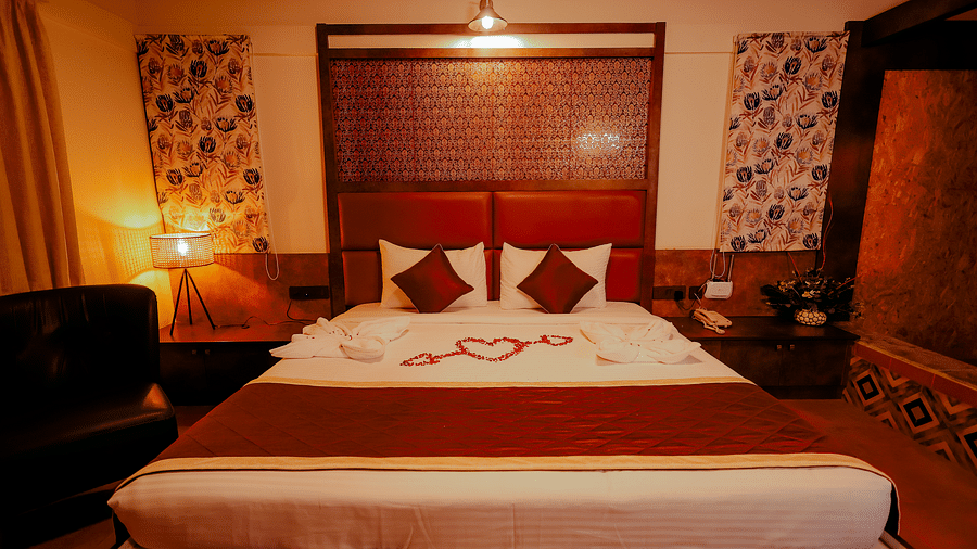 A room with a comfortable bed and warm lighting at Nirantara Resort & Spa, Bengaluru, featuring decorative towels and flowers.