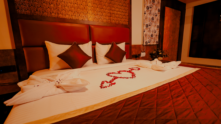 A neatly made bed with decorative towels and flowers in a room at Nirantara Resort & Spa