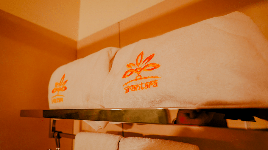 Close-up of a wall-mounted air-conditioning unit and towels at Nirantara Resort & Spa.