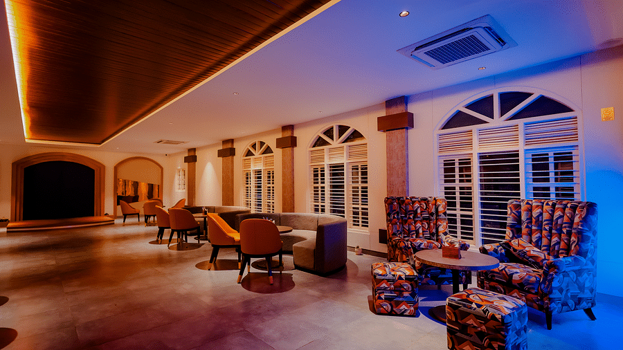 A spacious lounge area at Nirantara Resort & Spa with comfortable seating, decorative lighting, and a view of the outdoors.