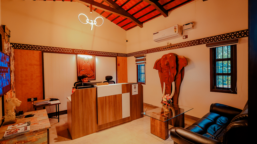 The interior of a building with a reception desk and seating area at Nirantara Resort & Spa, featuring a rustic design with wooden elements.