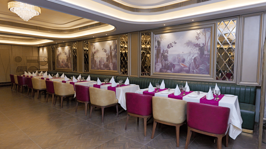 Spacious restaurant hall with neatly arranged dining tables and patterned ceiling at Nirvana Gateway.