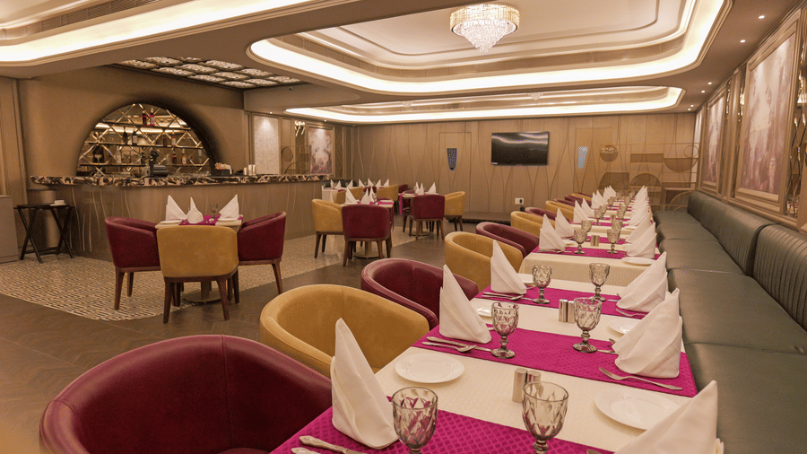 Restaurant dining area with arranged tables, fabric chairs, and ceiling lights at Nirvana Gateway.
