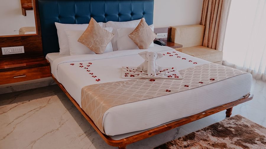 An image of a suite room featuring a bed, bed side tables, and a couch - Nisarga Lake Resort