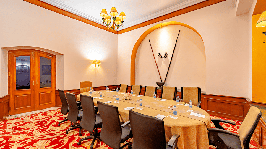 A long conference table with notepads and packed water bottles places in front of each chair surrounding it in the boardroom of Noor-Us-Sabah Palace, Bhopal.