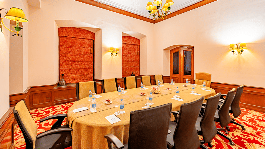 A boardroom with modern office chairs surrounding the conference table with well-placed stationery items at Noor-Us-Sabah Palace, Bhopal.