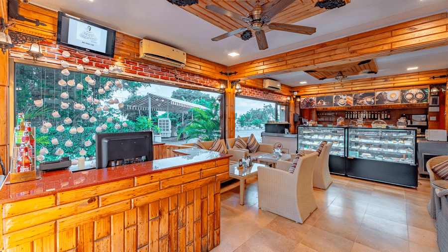 Indoor counter and seating area at Café Latte, located within Noor-Us-Sabah Palace, Bhopal, featuring wooden panelling and glass display cases.