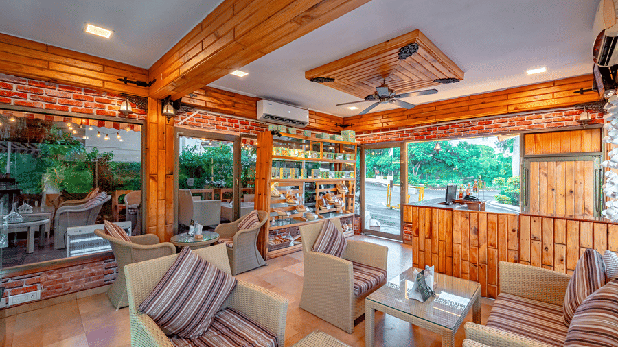 Indoor lounge at Café Latte, located within Noor-Us-Sabah Palace, Bhopal, featuring wicker armchairs with striped cushions and warm wooden interiors.