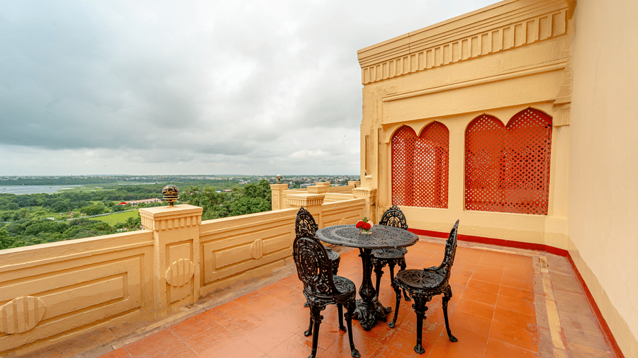 The private balcony of the Crown Club Suite at Noor-Us-Sabah Palace, showing a wrought-iron seating set for 2 with a stunning panoramic view of the lake and greenery.
