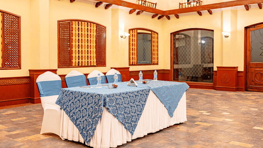 Close up of a table with packed water bottles kept on it, lined with 4 chairs in the Emperor Hall at Noor-Us-Sabah Palace, Bhopal.