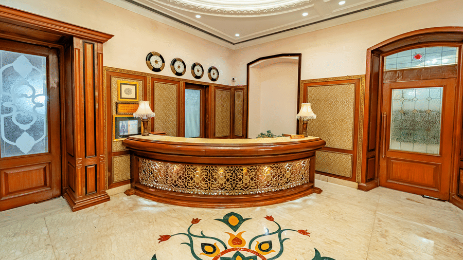 The reception desk at Noor-Us-Sabah Palace, Bhopal, with a beautiful marble design on the floor along with 4 wall clocks above the reception area.