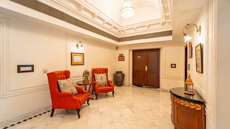 2 arm chairs with a cushion on each kept in the lobby area with white marble flooring at Noor-Us-Sabah Palace, Bhopal.