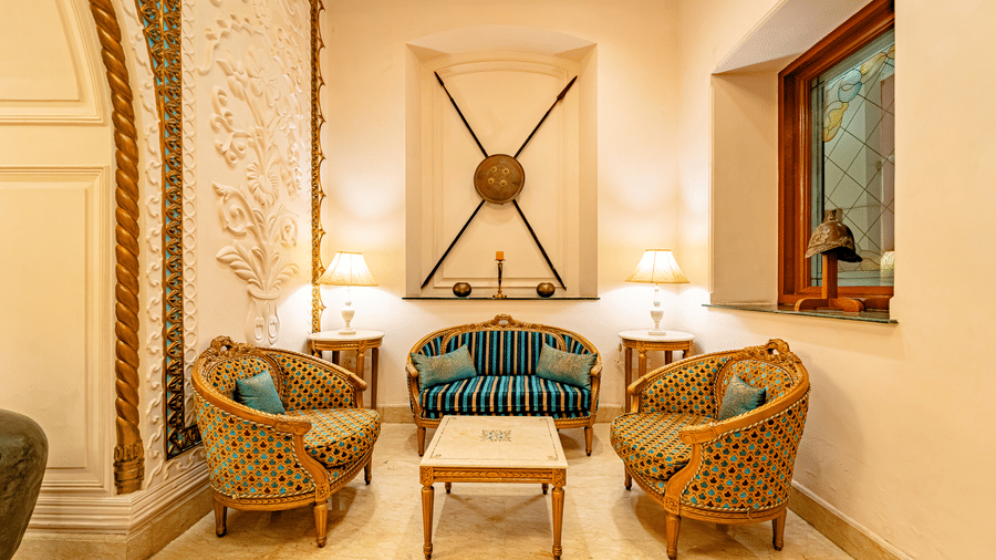 A common seating area in the lobby of Noor-Us-Sabah Palace, Bhopal, brightly lit with table lamps in the corners.