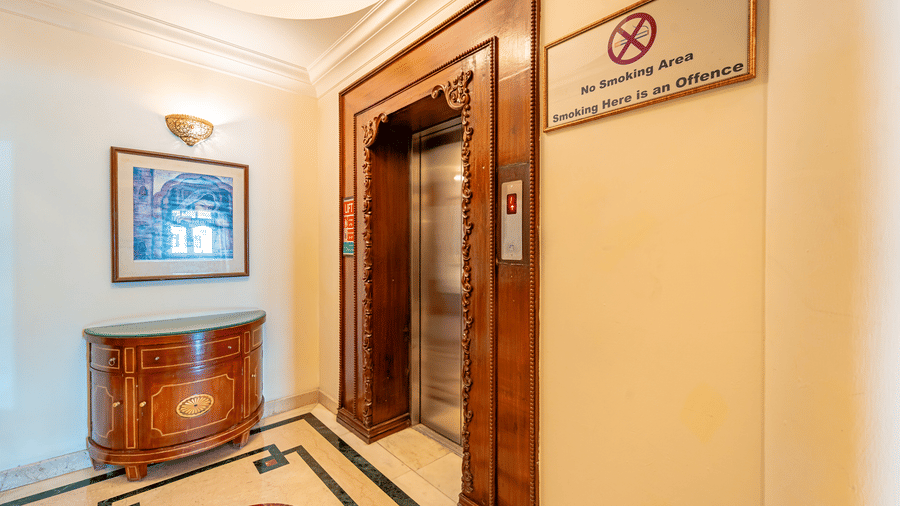 An elevator in the corner of the lobby with a sign board of 'No Smoking' besides it at Noor-Us-Sabah Palace, Bhopal.