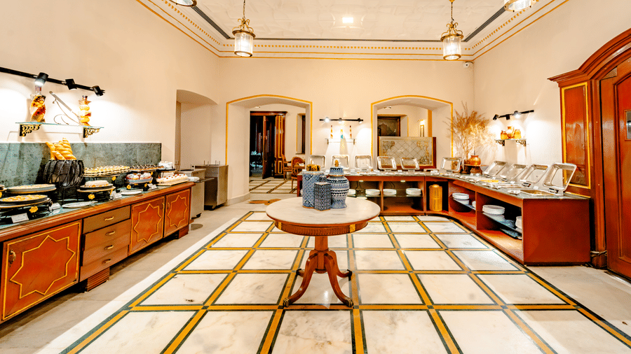 The buffet dining room at Marble Arch, located within Noor-Us-Sabah Palace, Bhopal, featuring patterned marble flooring and wooden service counters.
