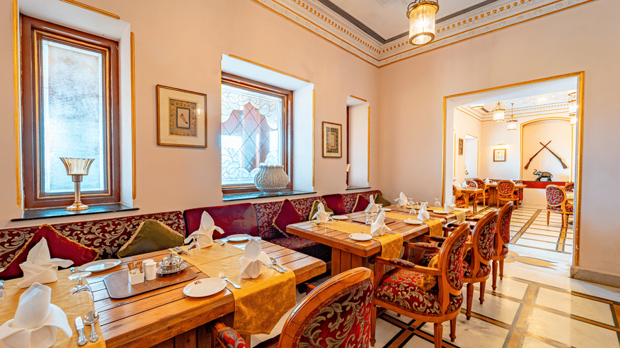 Neatly arranged dining tables at the Marble Arch restaurant with cutlery, hand towels, and glassware at Noor-Us-Sabah Palace, Bhopal.