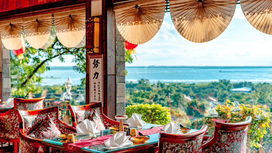 An indoor table set for guests at Ming Dynasty, located within Noor-Us-Sabah Palace, Bhopal, featuring large windows that provide a panoramic view of the lake.