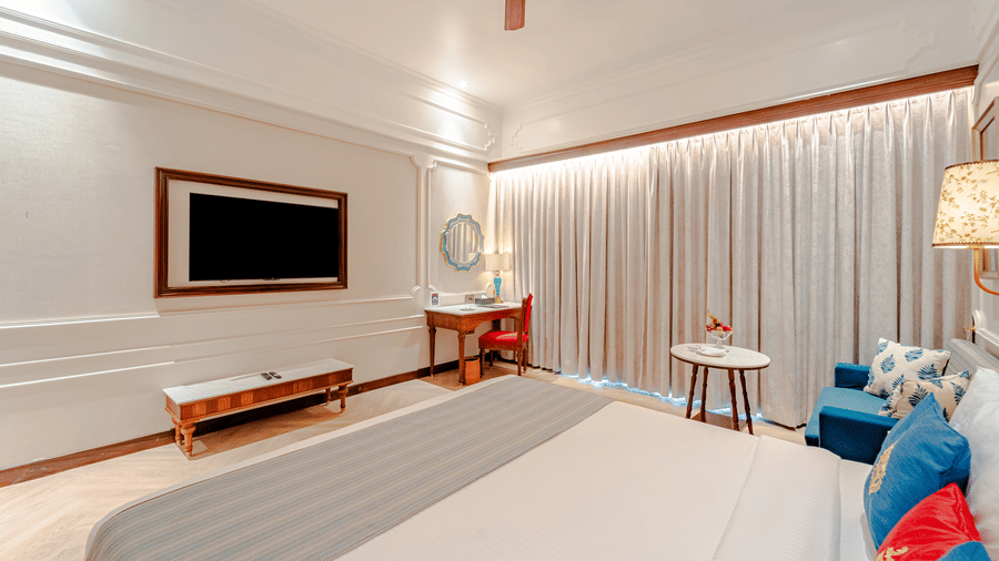 On overhead shot of the Royal Club Room featuring a double bed facing a wall-mounted television and a work desk in the corner at Noor-Us-Sabah Palace, Bhopal.