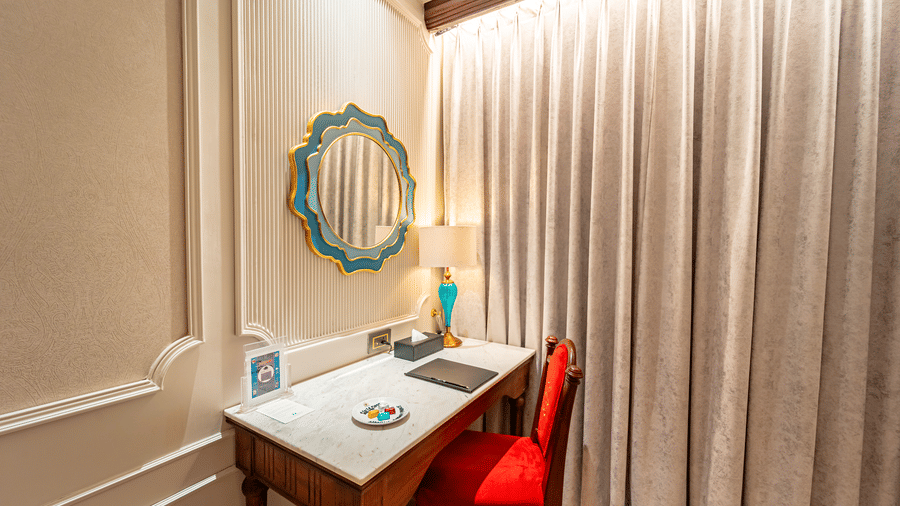 A close up of the work desk with a decorative round mirror mounted on the wall of Royal Club Room at Noor-Us-Sabah Palace, Bhopal.
