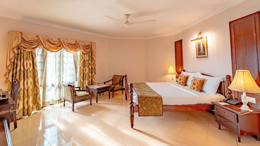 A wide-angle shot of the Standard Room at Noor-Us-Sabah Palace, Bhopal, highlighting the spacious layout, tiled flooring, and elegant traditional furniture.