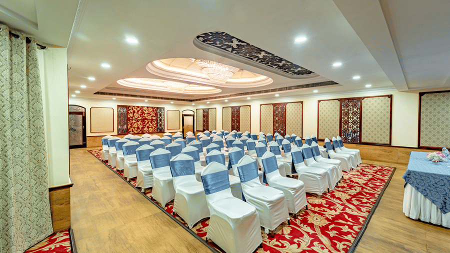 Corner view of the Viceroy banquet hall with chairs facing towards the a table covered with a blue-coloured table cloth at Noor-Us-Sabah Palace, Bhopal.