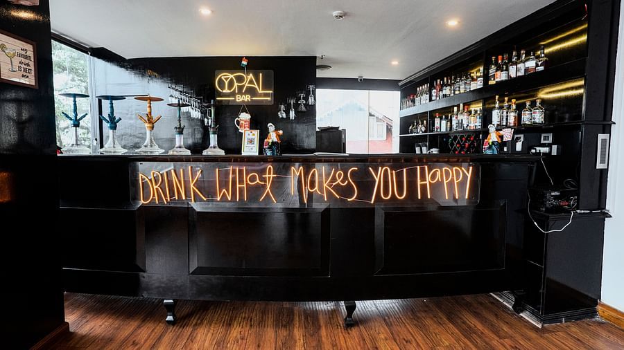 A wide shot of a dark bar counter at Orsino Spa Resort with shelves filled with various items, illuminated by warm lighting.