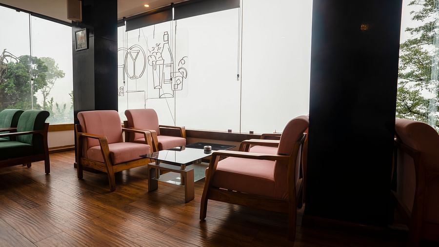 A wide shot of a seating area at Orsino Spa Resort with large windows and several armchairs with light-coloured upholstery and small tables on a polished wooden floor.