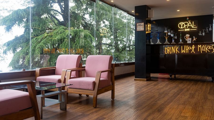 A wide shot of a bar at Orsino Spa Resort with large windows offering a view of pine trees.