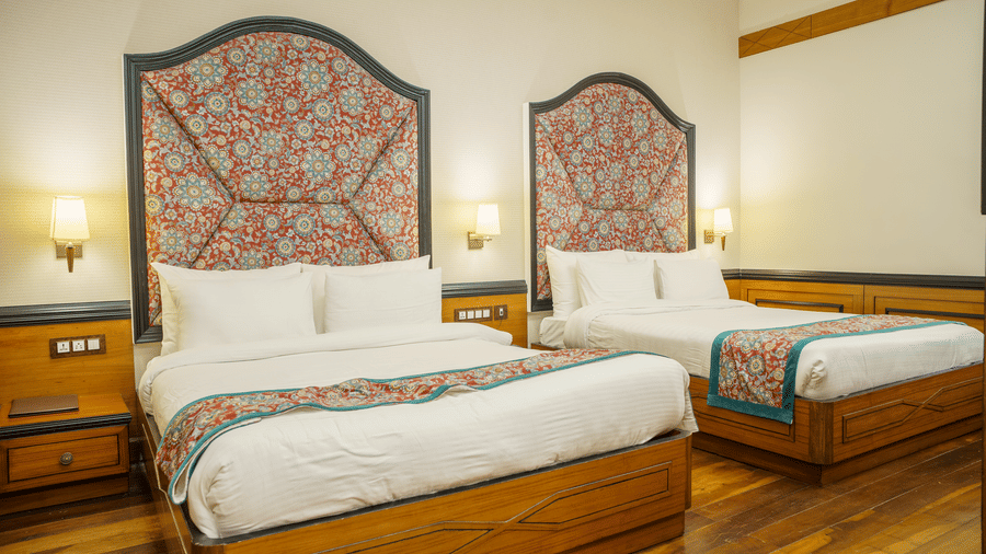 A Family Room at Orsino Spa Resort, Darjeeling, with 2 beds, each with a distinctive patterned headboard and a colourful throw.
