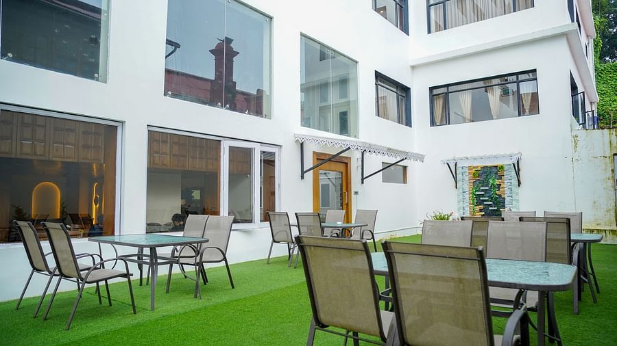 An outdoor dining area at Orsino Spa Resort with tables and chairs on green artificial turf, surrounded by white buildings.