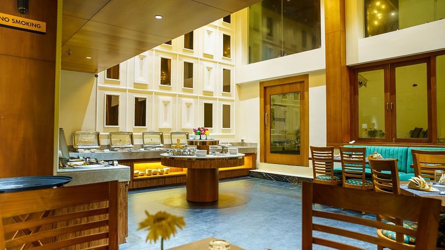 A spacious dining hall at Orsino Spa Resort with wooden tables, chairs, and multiple buffet stations.